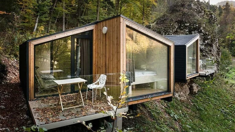 Forest cabin of glass and wood on a hillside outcrop, integrating nature into the design